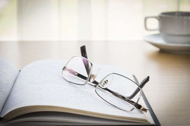 Lunettes posées sur un livre avec sur le bureau