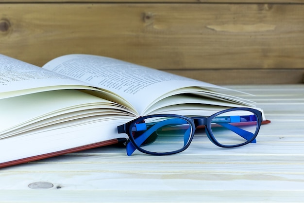 Photo lunettes près d'un livre ouvert sur planche de bois