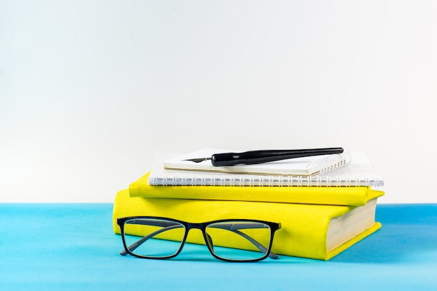 Lunettes de professeur, des livres et des lettres en bois sur une table bleue. Concept de jour d'école et d'enseignant. Espace de copie.