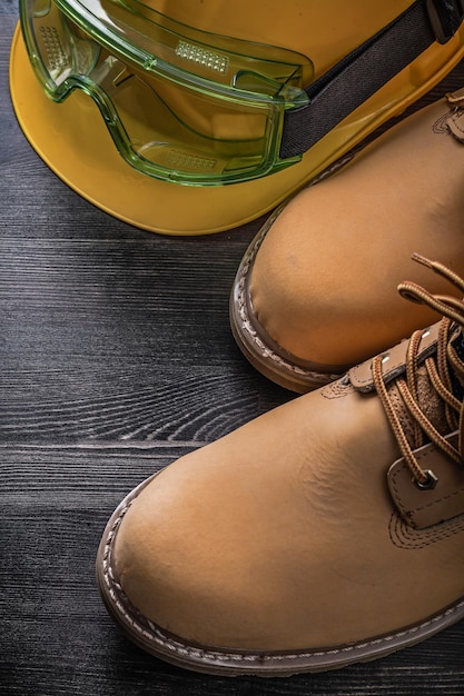 Lunettes de protection, casque de sécurité, bottes de sécurité sur planche de bois