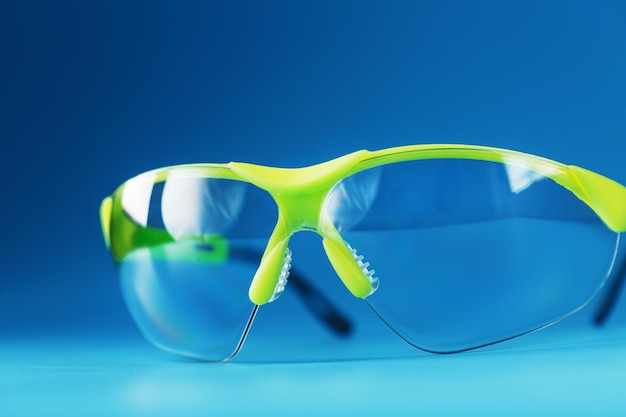 Lunettes de sécurité en polycarbonate transparent sur fond bleu. Protection oculaire fiable, espace libre