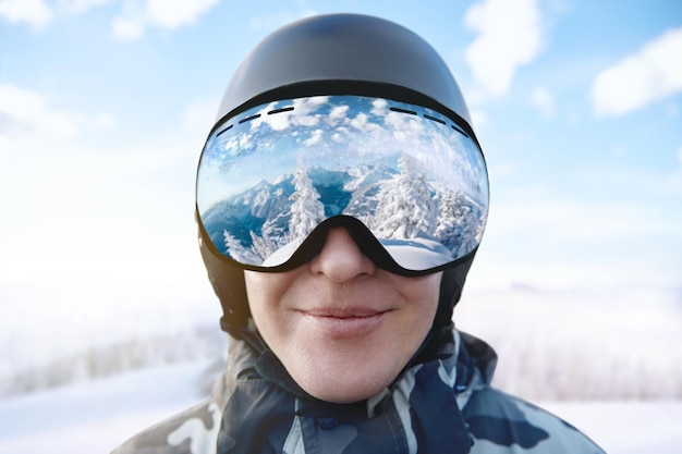 Photo lunettes de ski avec le reflet des montagnes enneigées. homme sur le fond de ciel bleu. sports d'hiver.