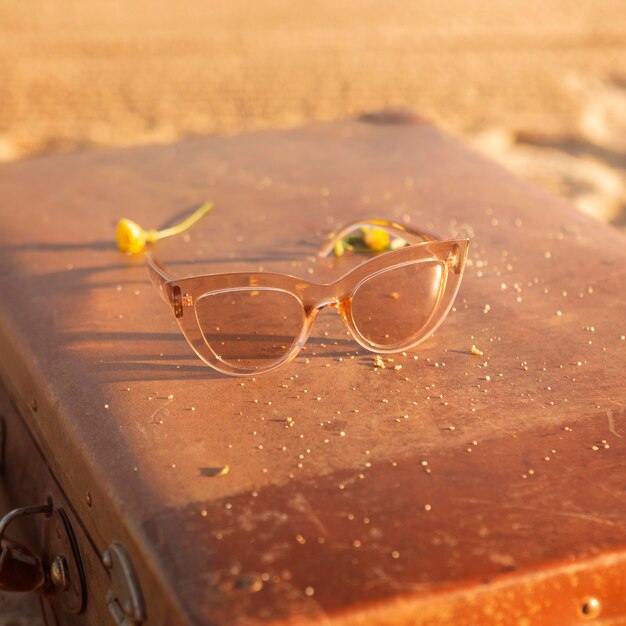 Photo lunettes de soleil à angle élevé sur la valise à la plage