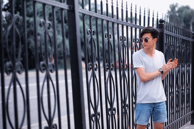 Lunettes de soleil asiatiques de jeune homme de mode dehors dans la ville