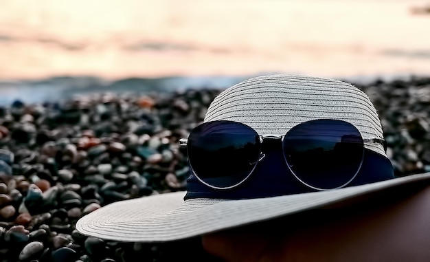 Photo lunettes de soleil et chapeau sur la plage le concept de voyage