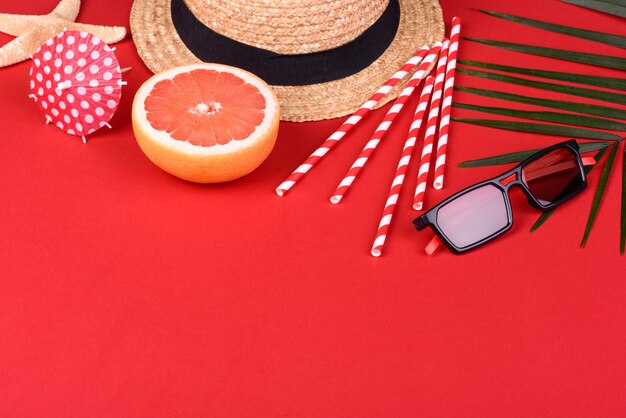 lunettes de soleil et chapeau sur une surface rouge