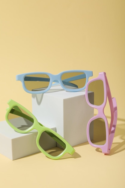 Des lunettes de soleil colorées sur des blocs blancs sur un fond beige