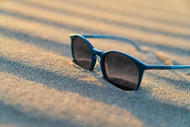 Lunettes de soleil dans le sable sur la plage. Été