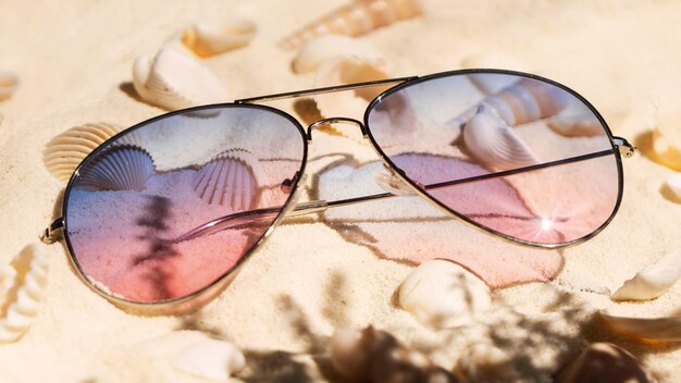 Lunettes de soleil dégradé violet et rose sur la plage Beaucoup de coquillages sur le sable tropical