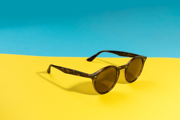 Lunettes de soleil élégantes ensoleillées sur une vue de dessus de fond bleu cyan et jaune vif isolé