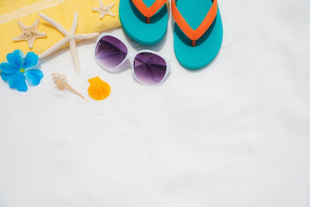 lunettes de soleil, étoile de mer, flip flop et coquille sur fond de plage de sable blanc