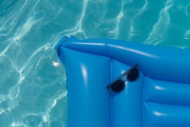 Lunettes de soleil sur un flotteur de piscine bleu Fond de vacances d'été