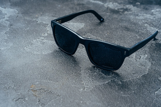 Lunettes de soleil homme foncé sur une surface en béton gris