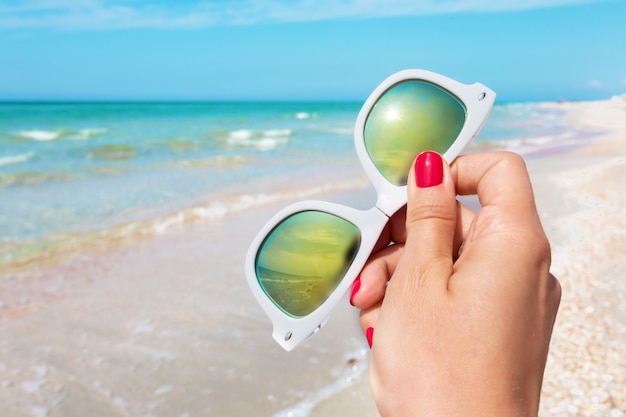 Lunettes de soleil à la main sur le fond de la plage