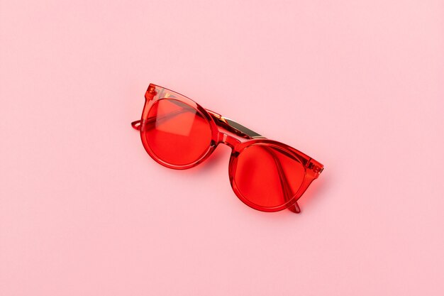 Lunettes de soleil à la mode rouges sur fond rose. Concept de vente d'été shopping mode