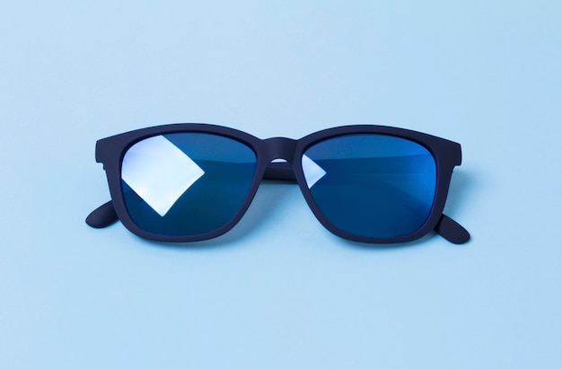 Lunettes de soleil modernes à la mode pour hommes sur table bleue.