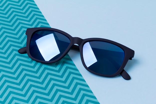 Lunettes de soleil modernes à la mode sur une table créative bleue