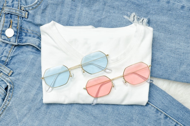 Lunettes de soleil multicolores sur un T-shirt blanc et un jean. Concept à la mode