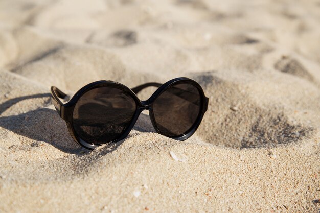 Lunettes de soleil sur la plage de sable en été.