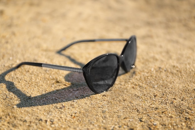 Photo des lunettes de soleil sur une plage de sable en gros plan