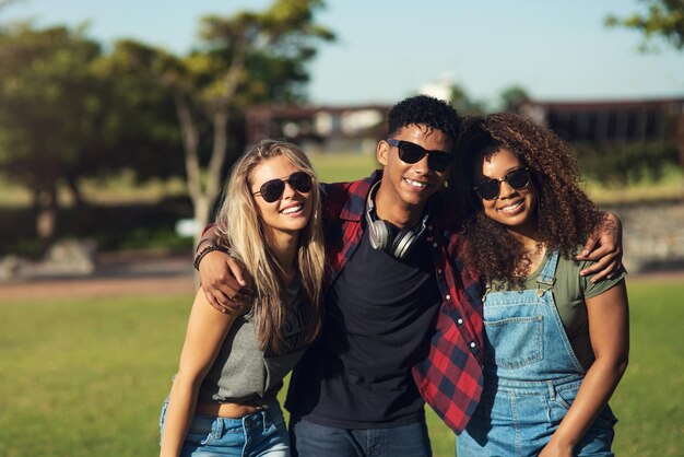 Lunettes de soleil sur Portrait d'un groupe de jeunes amis joyeux posant pour une photo ensemble tout en portant des lunettes de soleil à l'extérieur dans un parc