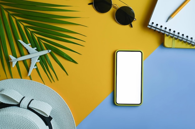 Lunettes de soleil pour ordinateur portable chapeau de téléphone intelligent à plat et feuilles de palmier tropical sur fond jaune Concept de vacances d'été