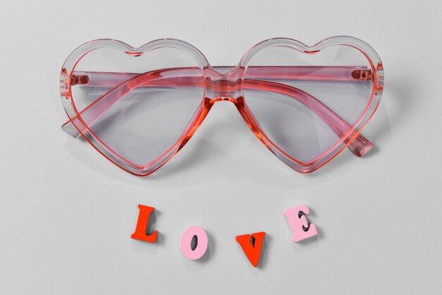 Photo lunettes de soleil roses sur fond bleu avec texte d'amour. vue de dessus.