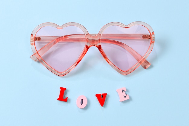 Lunettes de soleil roses sur fond bleu avec texte d'amour