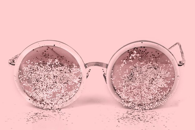 Lunettes de soleil roses avec paillettes sur fond rose