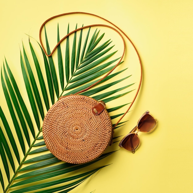 Lunettes de soleil sac rond en rotin sur fond jaune Culture carrée Vue de dessus avec espace de copie Sac en bambou à la mode et chaussures blanches Mode d'été mise à plat Concept de vacances de voyage