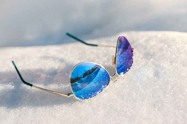 lunettes de soleil se trouvent sur la neige duveteuse blanche sur une journée ensoleillée, gros plan, arrière-plan, journée d'hiver
