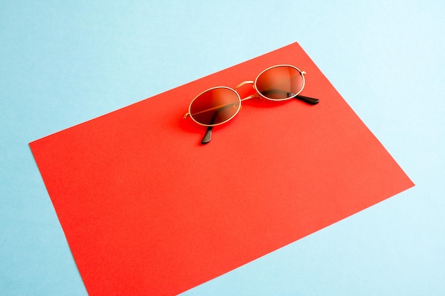 Lunettes de soleil simples à plat sur fond de papier rouge