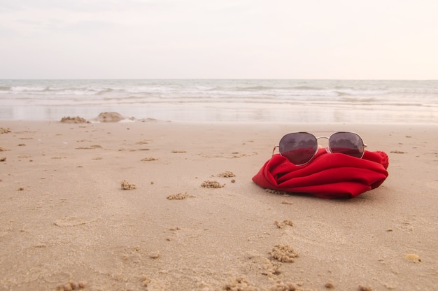 Lunettes de soleil avec tissu rouge sur le sable