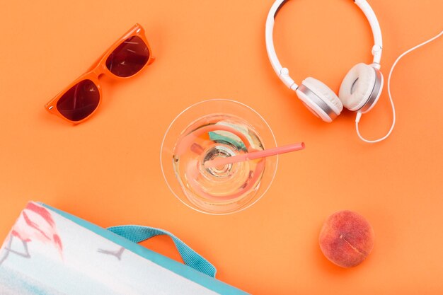 lunettes de soleil verre avec boisson écouteurs couverture de pêche sur fond orange style minimal d'été