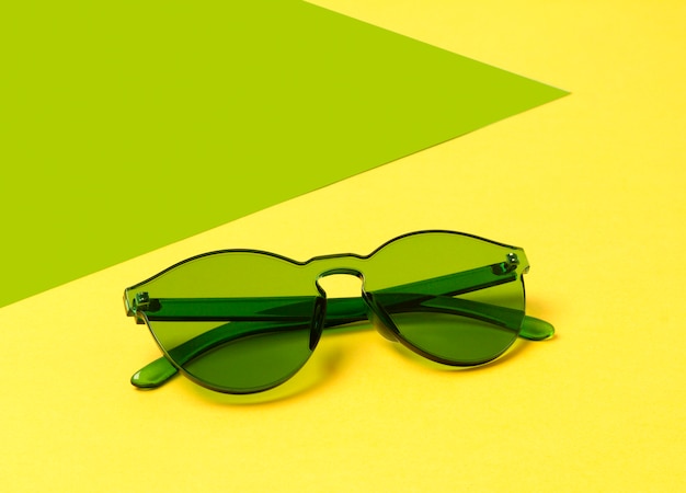 Lunettes de soleil vertes à la mode modernes sur une table jaune créative