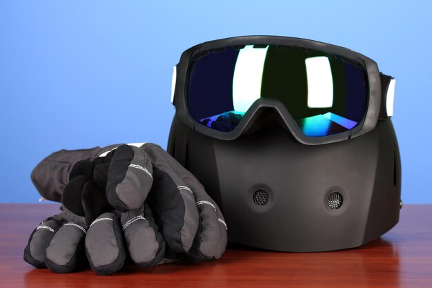 Des lunettes de sport d'hiver, un casque et des gants sur fond bleu