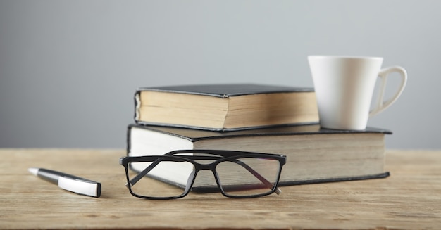 Lunettes, stylo, livre sur table en bois.