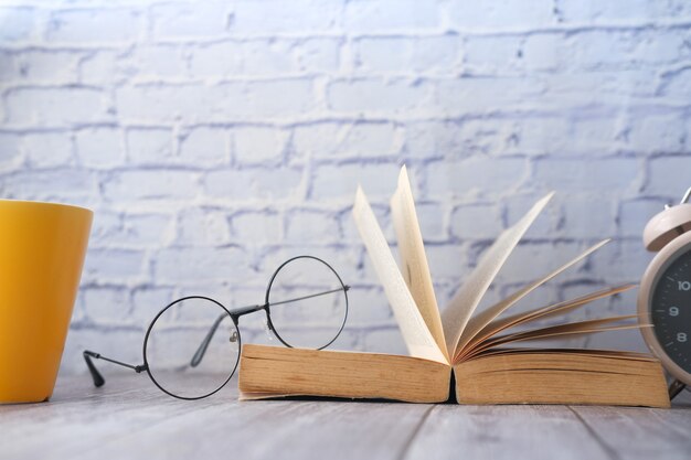 Lunettes de tasse à livre ouvert et un crayon sur une table en bois