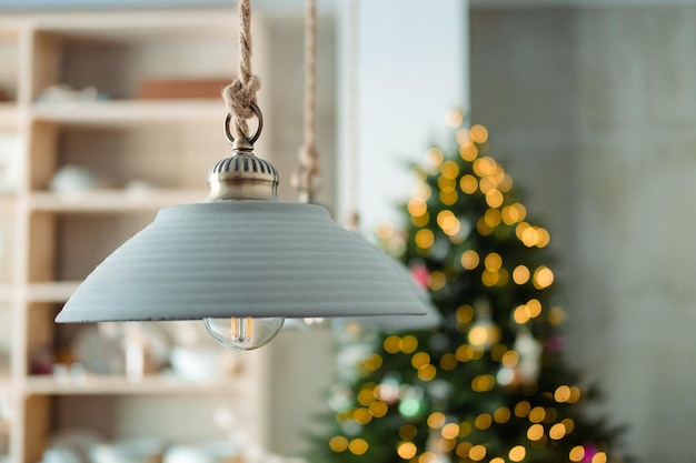 Un lustre en forme d'assiette sur fond d'étagère pour la vaisselle et un sapin de Noël avec une guirlande