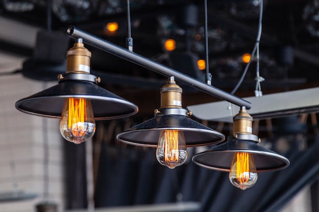 Lustres de loft en fer noir avec lampes Edison sur fond noir, bokeh.