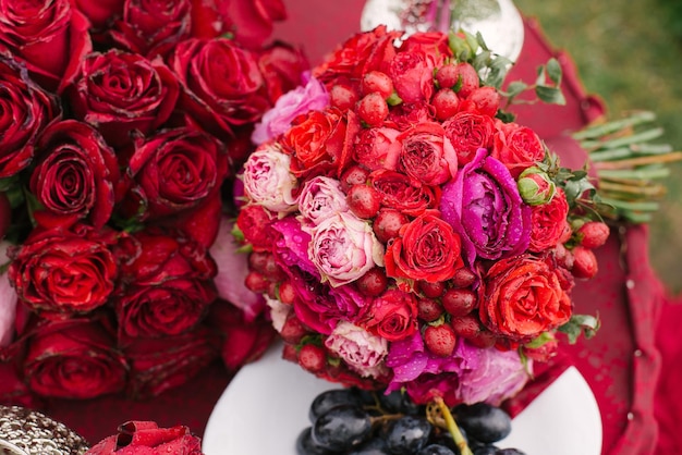 Luxueux beau bouquet de mariage lumineux de la mariée avec des roses et des baies de fleurs rouges et roses