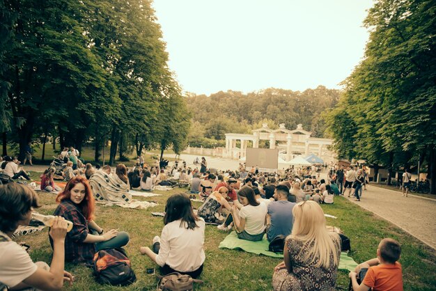 Photo lvivraine 1er juin 2018 personnes assises sur l'herbe dans un parc de la ville regardant un film dans un cinéma en plein air