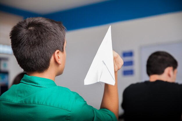 Lycéen coquin lançant un avion en papier pendant les cours