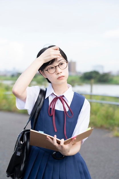 Lycéen féminin asiatique étudiant avec une expression sérieuse à l'extérieur