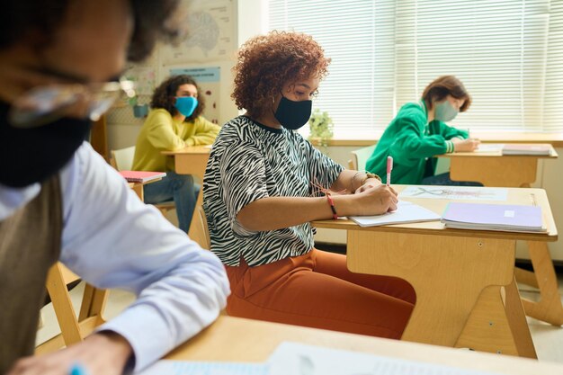 Lycéenne féminine écrivant des notes dans un cahier entre camarades de classe