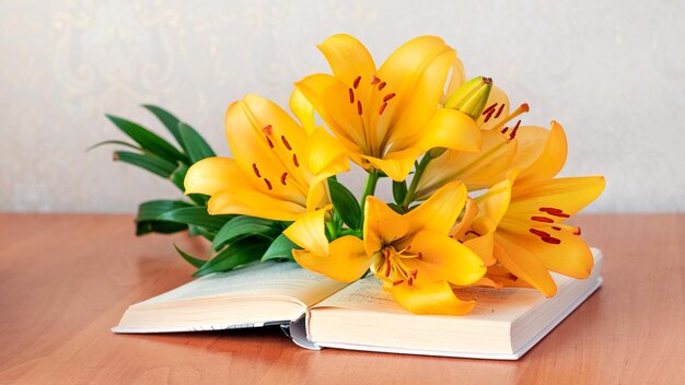 Lys orange sur un livre ouvert dans la chambre sur la table