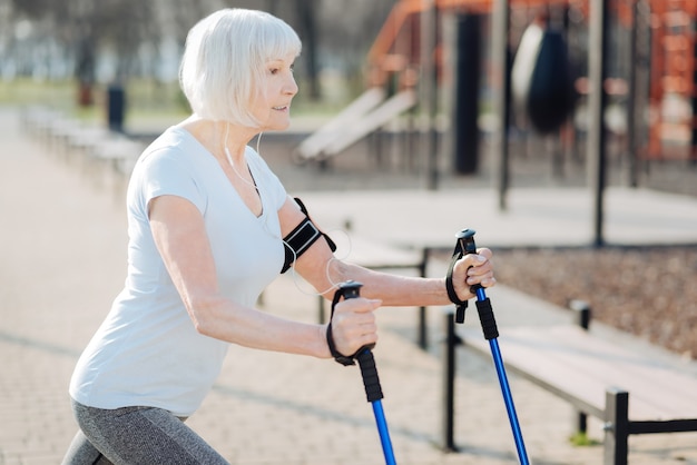 Ma belle journée. Alerte femme blonde souriante et à l'aide de béquilles pendant l'exercice