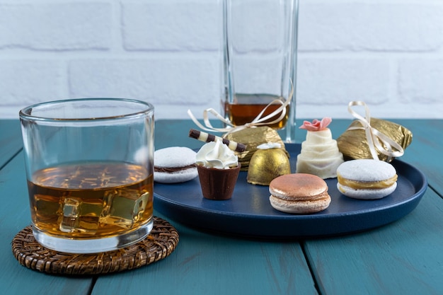 Macaron à côté d'un petit verre de chocolat avec crème fouettée, truffe camée aux noix et whisky