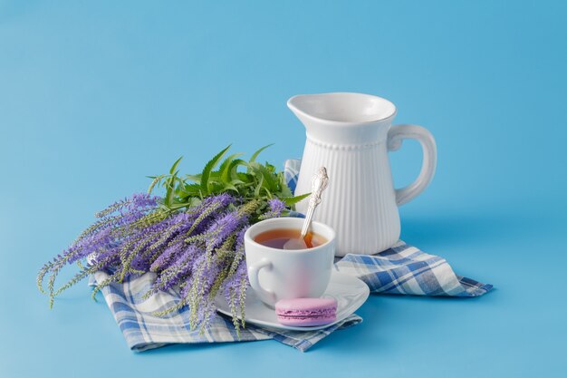 Macaron de couleur pastel avec du café sur la surface bleue