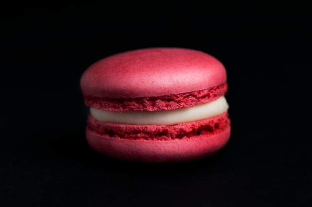 Macaron rose doux isolé sur fond noir